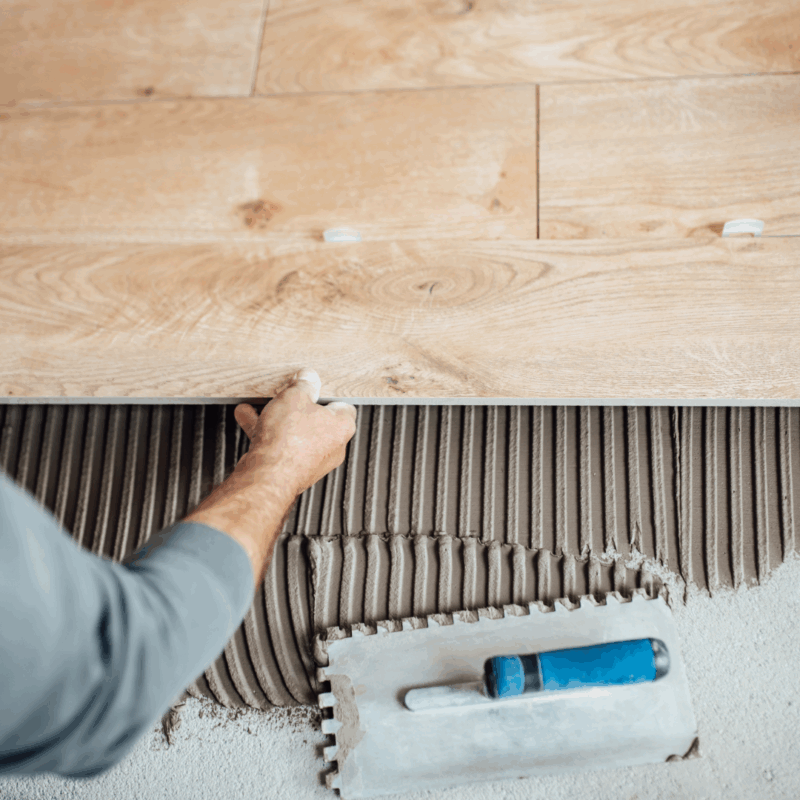 Hombre instalando piso de porcelanato con herramientas de colocación, ilustrando errores comunes durante la instalación