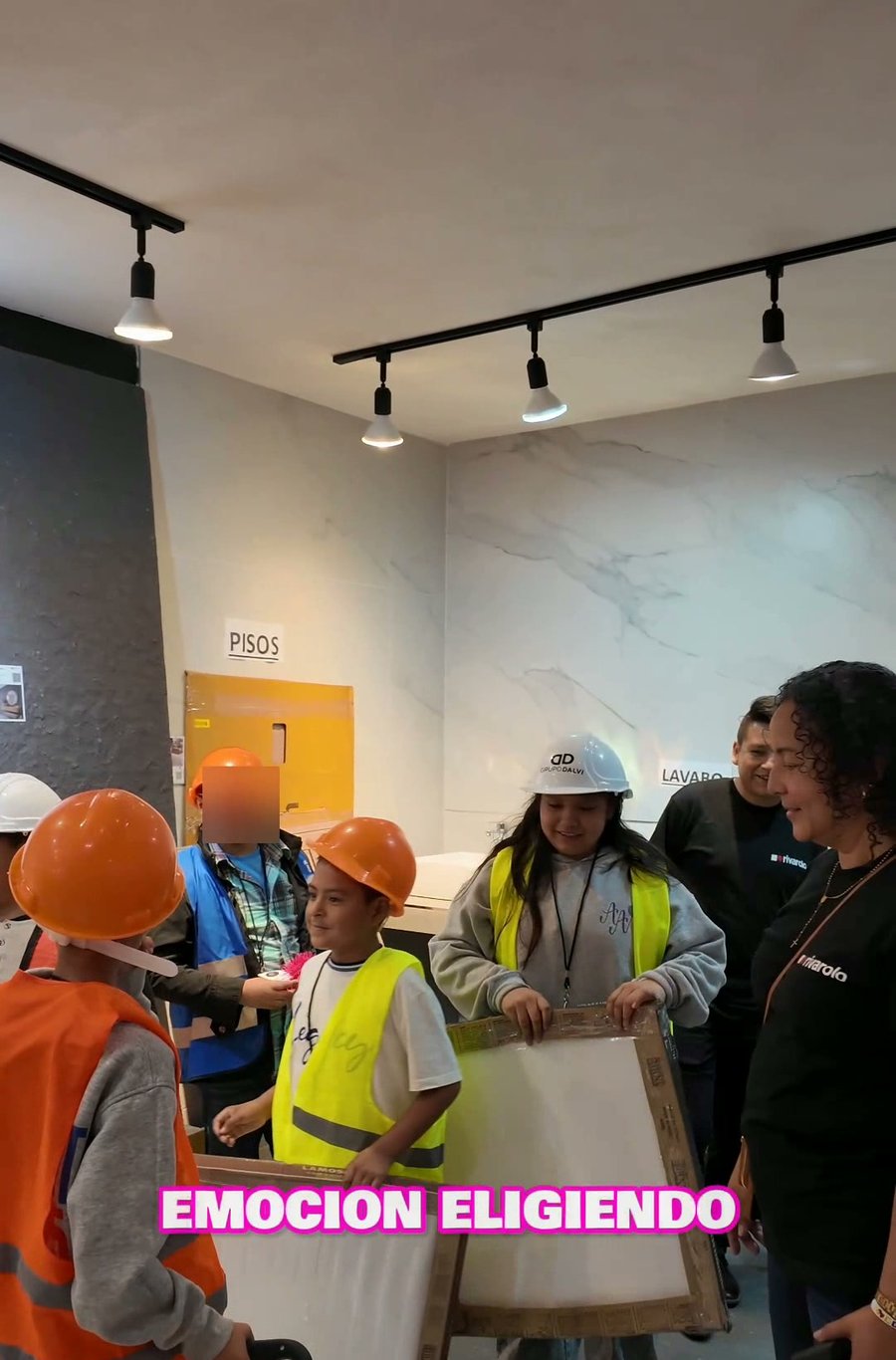 Ninos con cascos naranjas aprendiendo a instalar pisos en showroom Dalvi