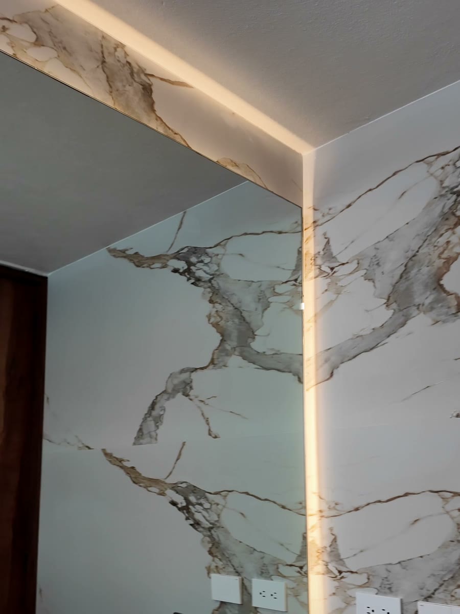 Baño vestido en porcelánico símil mármol dorado con iluminación perimetral