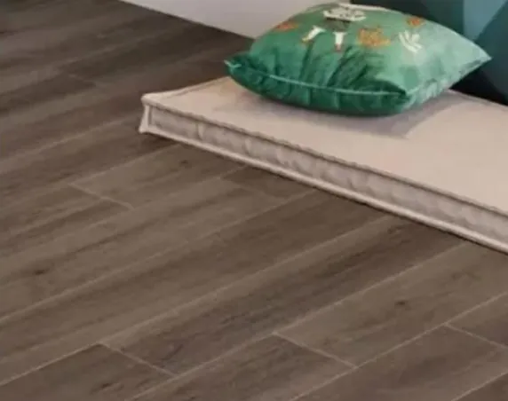 Detalle del piso en un ambiente de referencia del modelo Brujas Cedro 20x120 cm, cerámico no rectificado mate
