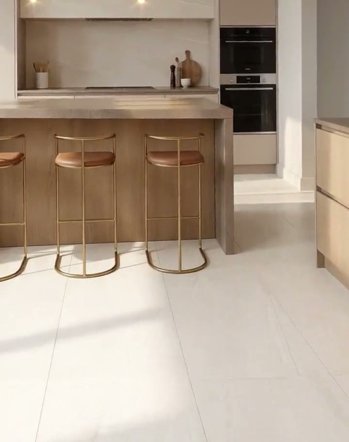Cocina luminosa con piso mate blanco hueso y bancos de latón, escena del video de la serie Pisos mate en tendencia